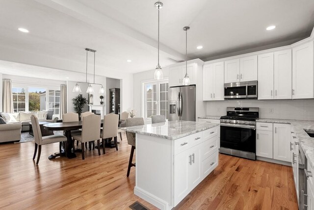 kitchen with a center island, open floor plan, light wood-style flooring, and appliances with stainless steel finishes