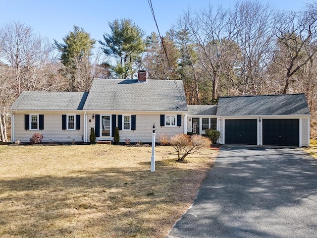 view of front of house featuring aphalt driveway, an attached garage, a chimney, and a front yard