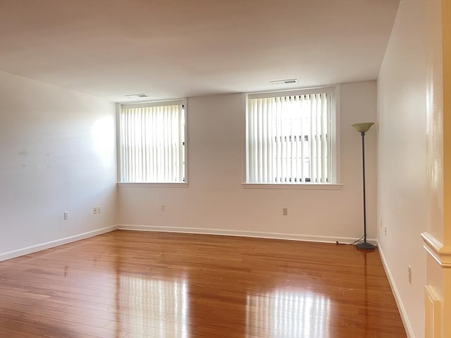 empty room featuring wood finished floors, healthy amount of natural light, and baseboards