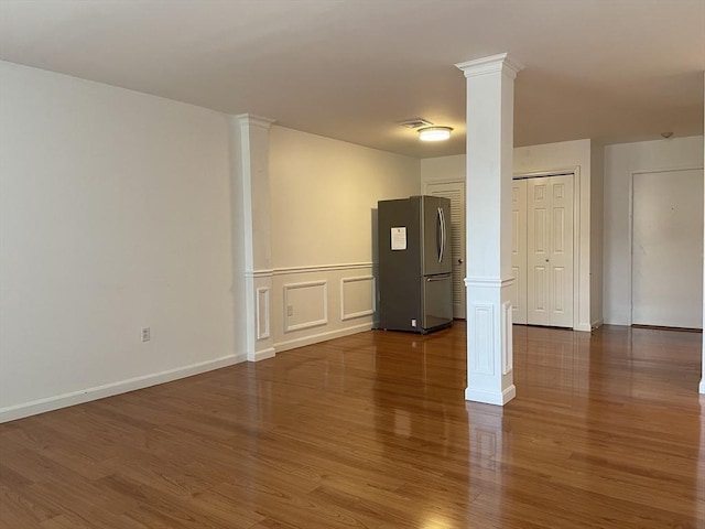 unfurnished living room with ornate columns, dark wood-style floors, and baseboards