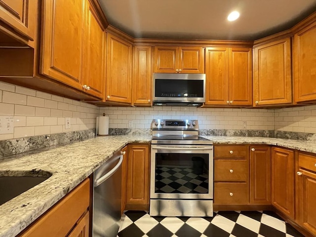 kitchen with appliances with stainless steel finishes, tile patterned floors, decorative backsplash, and brown cabinetry