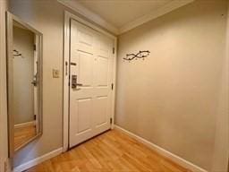 entryway with ornamental molding and light hardwood / wood-style flooring