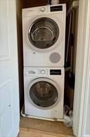 clothes washing area featuring stacked washer and clothes dryer