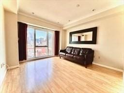 sitting room with crown molding and light hardwood / wood-style flooring