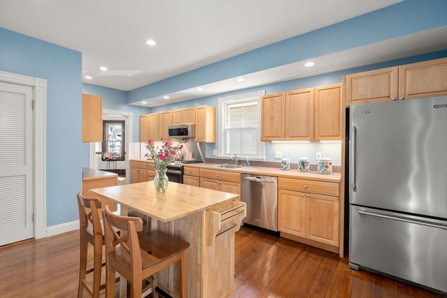 kitchen featuring wooden counters, dark wood-style flooring, a sink, light brown cabinetry, and appliances with stainless steel finishes