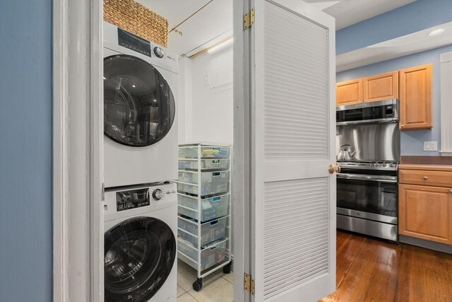 washroom featuring dark wood finished floors, laundry area, and stacked washer / dryer