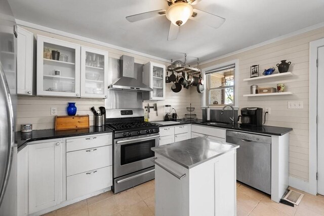 kitchen featuring dark countertops, appliances with stainless steel finishes, a sink, and wall chimney exhaust hood