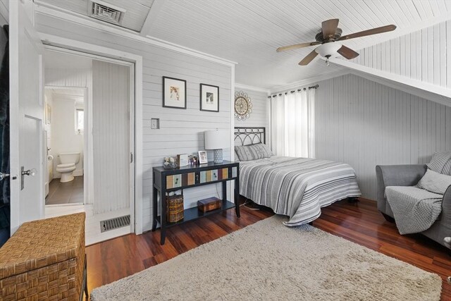 bedroom with wooden walls, ceiling fan, visible vents, and wood finished floors