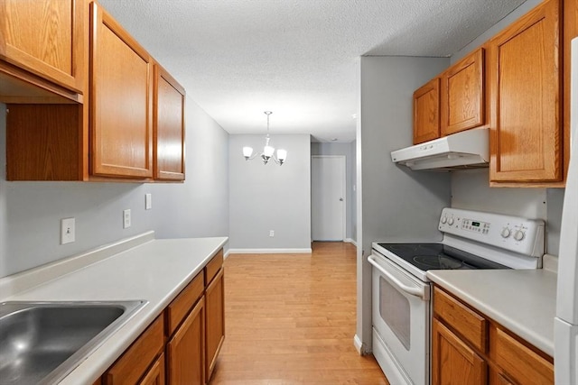 49 Village Brook Ln Unit 2, Natick, MA 01760 - kitchen with under cabinet range hood, white range with electric stovetop, light wood finished floors, light countertops, and a chandelier