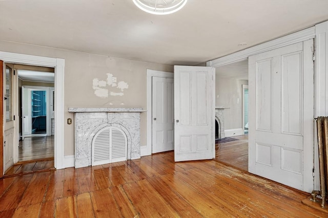 unfurnished living room with a fireplace with flush hearth, baseboards, and hardwood / wood-style floors