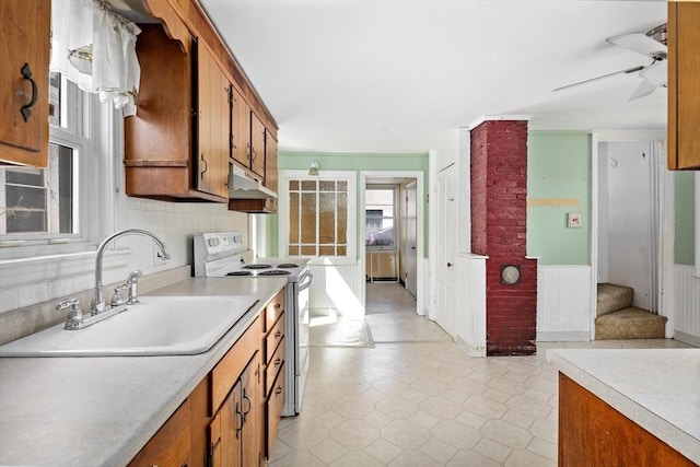 kitchen featuring brown cabinetry, white electric range, under cabinet range hood, and a sink