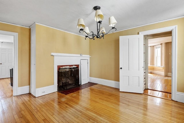 unfurnished living room with a fireplace with flush hearth, crown molding, a chandelier, and hardwood / wood-style floors