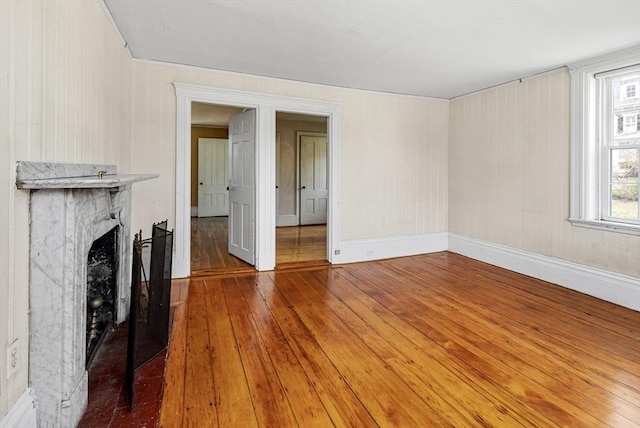 unfurnished living room with wood-type flooring, a fireplace, and baseboards