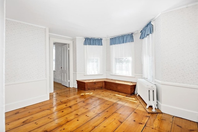 unfurnished room featuring radiator, ornamental molding, wallpapered walls, and light wood-style flooring