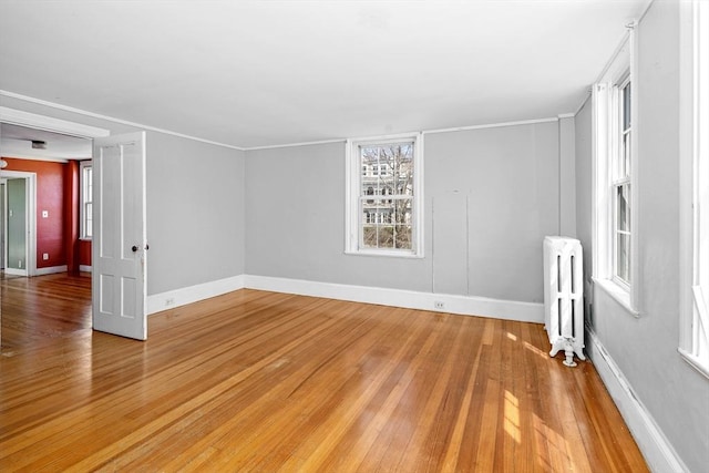 unfurnished room featuring radiator, baseboards, and light wood-type flooring