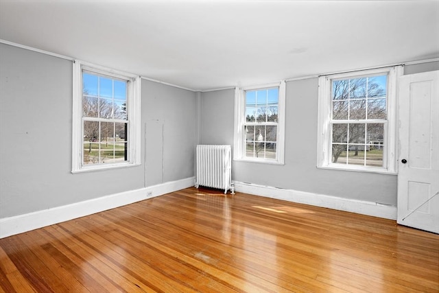 unfurnished room with radiator, baseboards, and wood finished floors