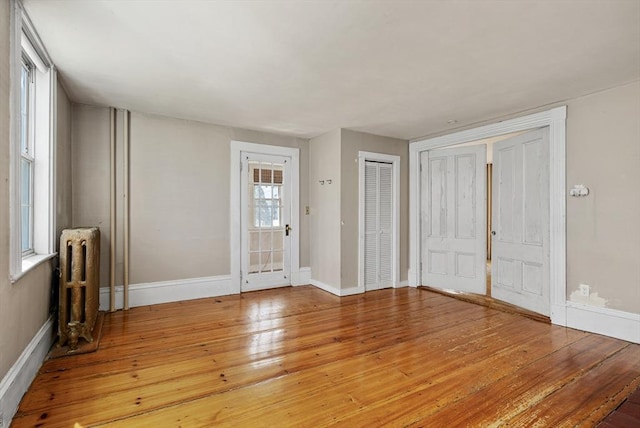 foyer entrance featuring radiator heating unit, light wood finished floors, and baseboards