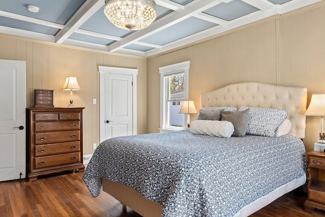 bedroom featuring ornamental molding, beam ceiling, hardwood / wood-style flooring, coffered ceiling, and a notable chandelier