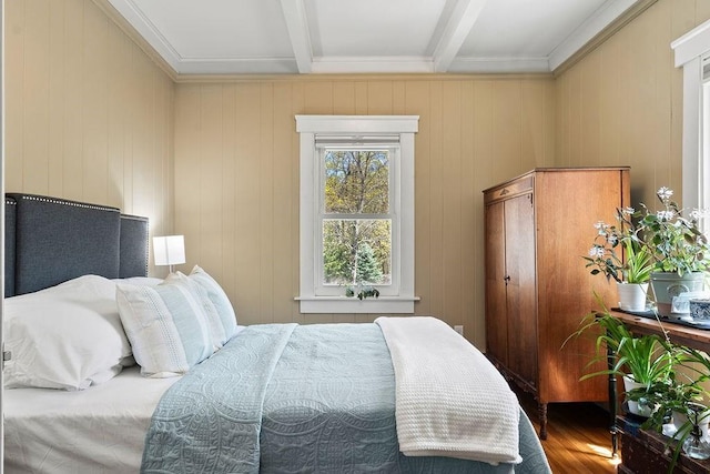 bedroom with crown molding, beam ceiling, and wood finished floors