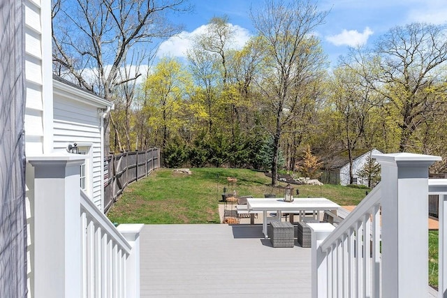 wooden terrace featuring fence, outdoor dining space, and a lawn
