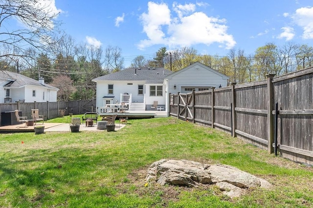 rear view of property with a lawn, a fenced backyard, a fire pit, and a deck