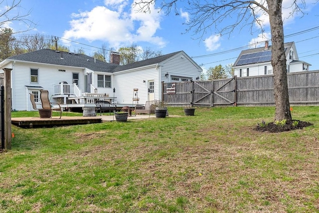 back of house featuring a gate, fence, a yard, and a deck