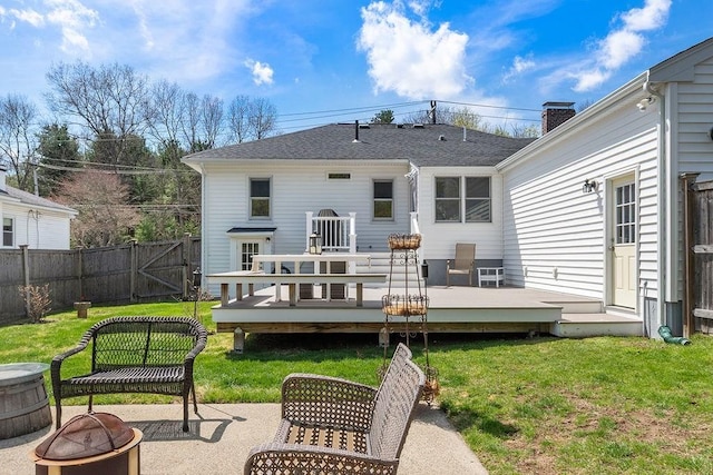 rear view of property featuring a lawn, an outdoor fire pit, fence, and a deck