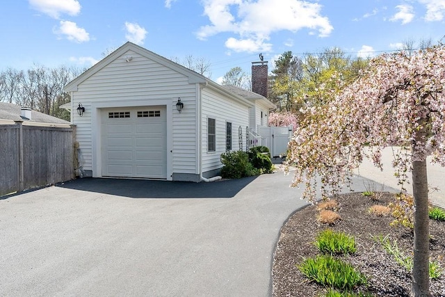 detached garage featuring aphalt driveway and fence