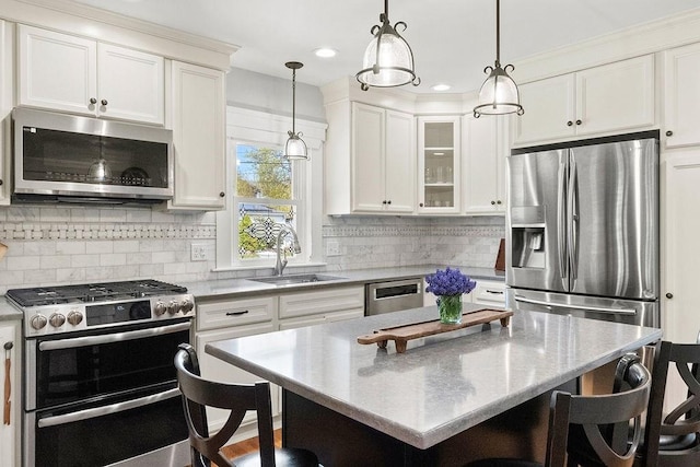 kitchen with white cabinets, a sink, a kitchen breakfast bar, stainless steel appliances, and pendant lighting