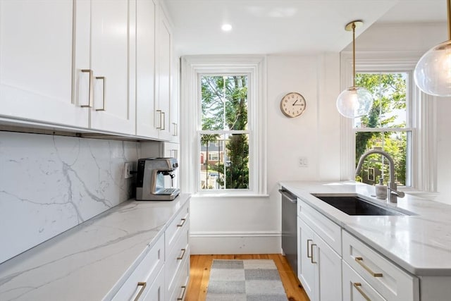 kitchen with dishwasher, sink, decorative backsplash, light stone countertops, and white cabinetry