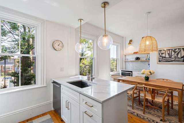 kitchen with light stone countertops, sink, stainless steel dishwasher, kitchen peninsula, and white cabinets