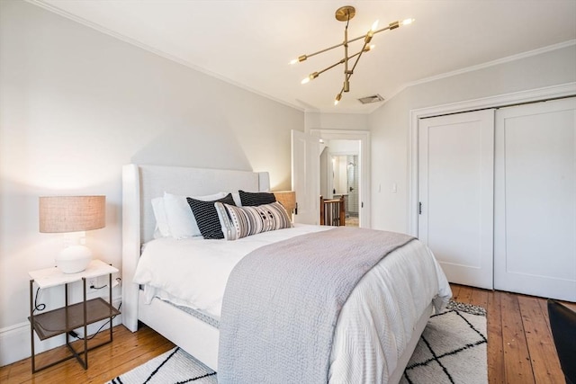 bedroom featuring crown molding, a closet, wood-type flooring, and a notable chandelier