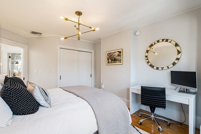 bedroom with ornamental molding, a closet, hardwood / wood-style floors, and an inviting chandelier