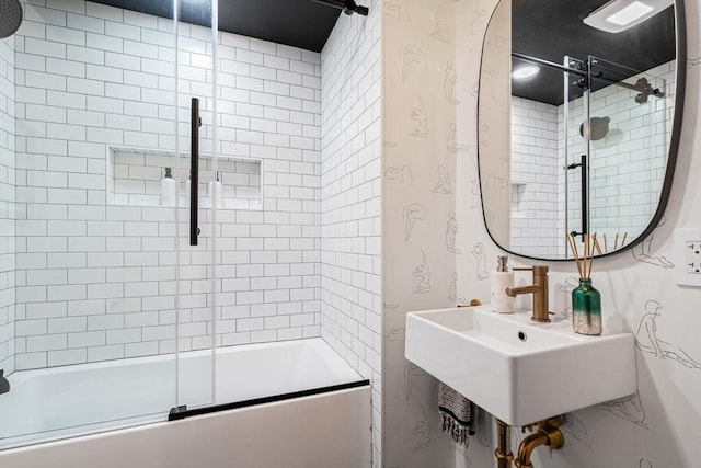 bathroom with sink and bath / shower combo with glass door