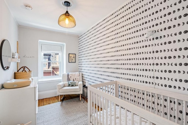 bedroom with a crib and hardwood / wood-style flooring