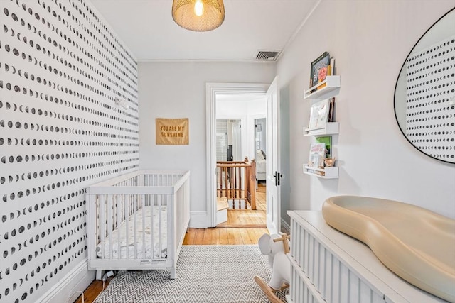 bedroom with light hardwood / wood-style flooring and a nursery area