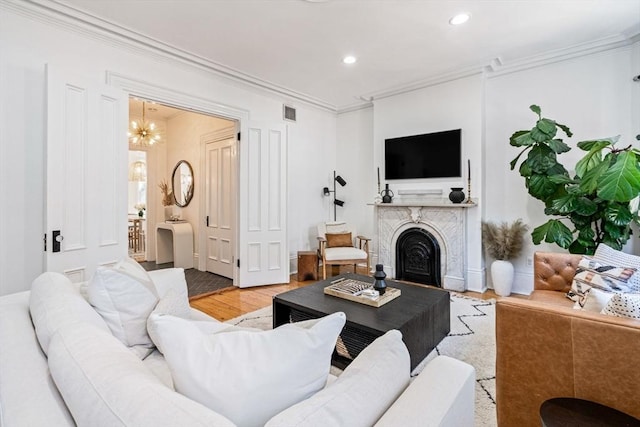 living room featuring light hardwood / wood-style flooring, a notable chandelier, and ornamental molding