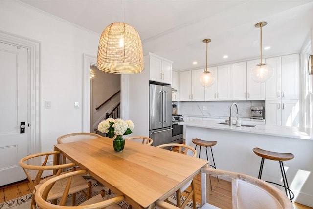 kitchen with light wood-type flooring, backsplash, stainless steel appliances, sink, and white cabinets