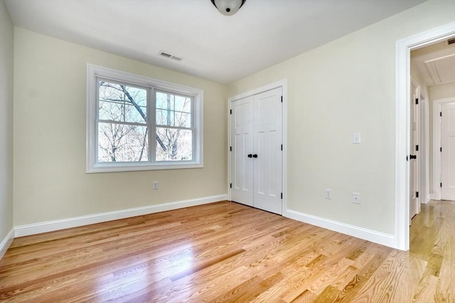 interior space featuring visible vents, a closet, light wood-style floors, baseboards, and attic access