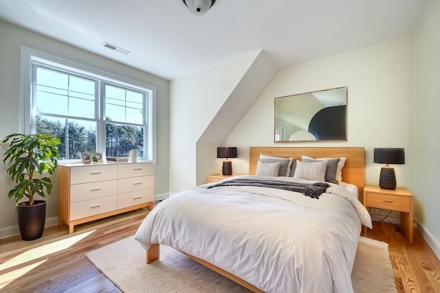 bedroom with light wood-type flooring, baseboards, and visible vents