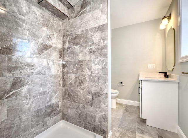 full bath with a tile shower, toilet, vanity, and baseboards