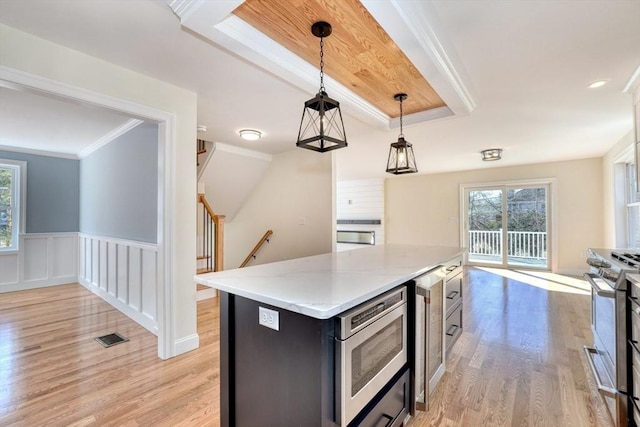 kitchen featuring visible vents, ornamental molding, stainless steel appliances, a raised ceiling, and light wood-type flooring