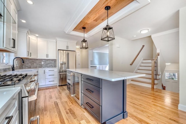 kitchen featuring a sink, stainless steel appliances, white cabinets, light wood-style floors, and tasteful backsplash