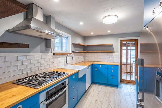 22 Sherman Ave, Northampton, MA 01060 - kitchen with appliances with stainless steel finishes, wall chimney exhaust hood, blue cabinetry, a sink, and wooden counters