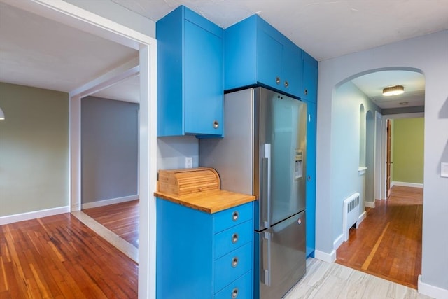22 Sherman Ave, Northampton, MA 01060 - kitchen featuring blue cabinets, radiator heating unit, arched walkways, and light wood-type flooring