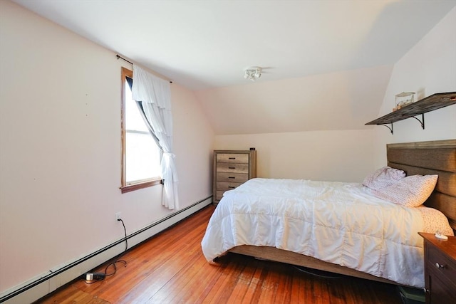 bedroom with wood-type flooring, a baseboard heating unit, and vaulted ceiling