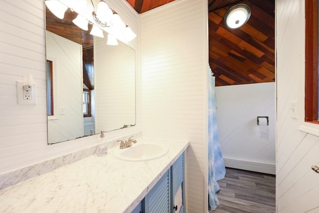 bathroom with a baseboard heating unit, wood walls, wood finished floors, and vanity