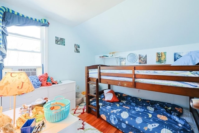 bedroom with wood finished floors and lofted ceiling