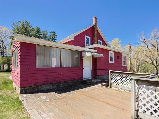 rear view of property featuring a wooden deck and a chimney