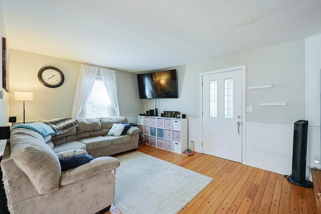 living area featuring light wood-style flooring and a wainscoted wall